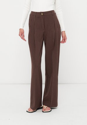 Pantalon large à rayures marron porté avec un haut blanc et des sandales beiges, visible de la taille aux pieds sur fond blanc.