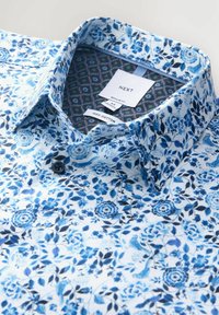 Niebieska bawełniana koszula w kwiaty, o regularnym kroju, z kołnierzykiem zapinanym na guziki, ciemnymi guzikami oraz kontrastującym, wzorzystym materiałem od środka.