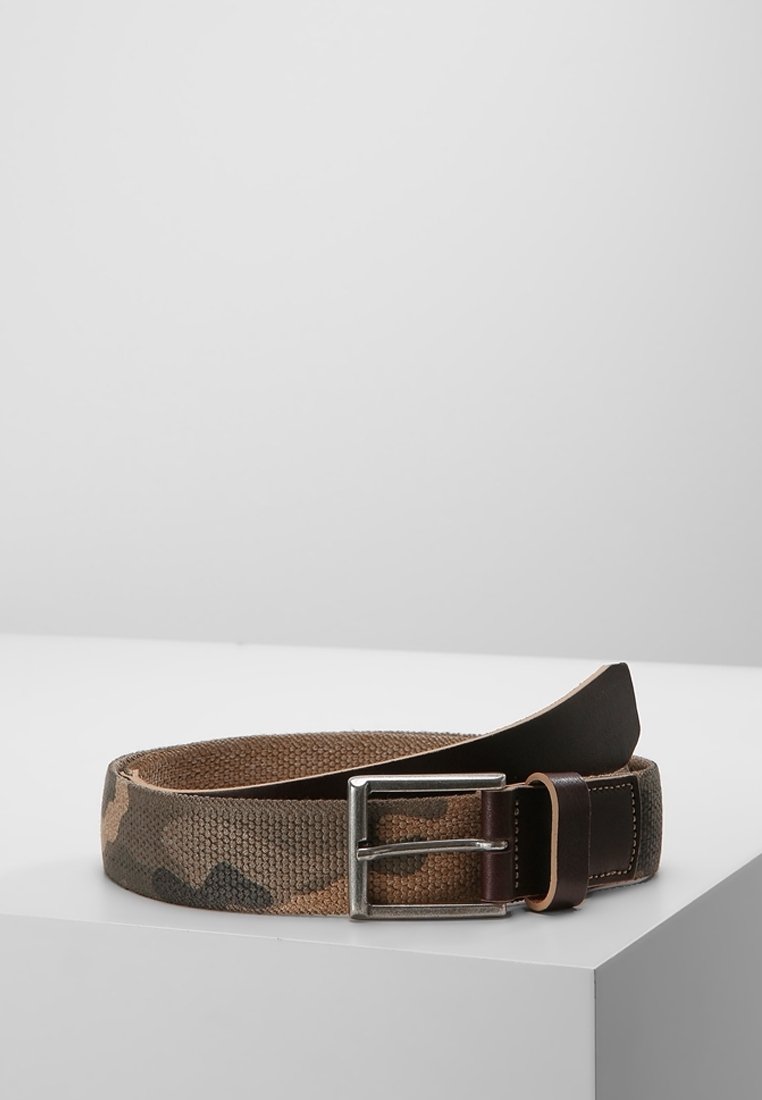 Brązowo-zielony pas w kamuflaż, z klamrą z ciemnobrązowej skóry i srebrnym metalowym trzpieniem, leżący na białej powierzchni.