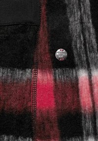 Karierter Stoff in den Farben Schwarz, Rot und Grau mit einer weichen Textur. Enthält einen silbernen Knopf mit "Street One"-Markenlogo.