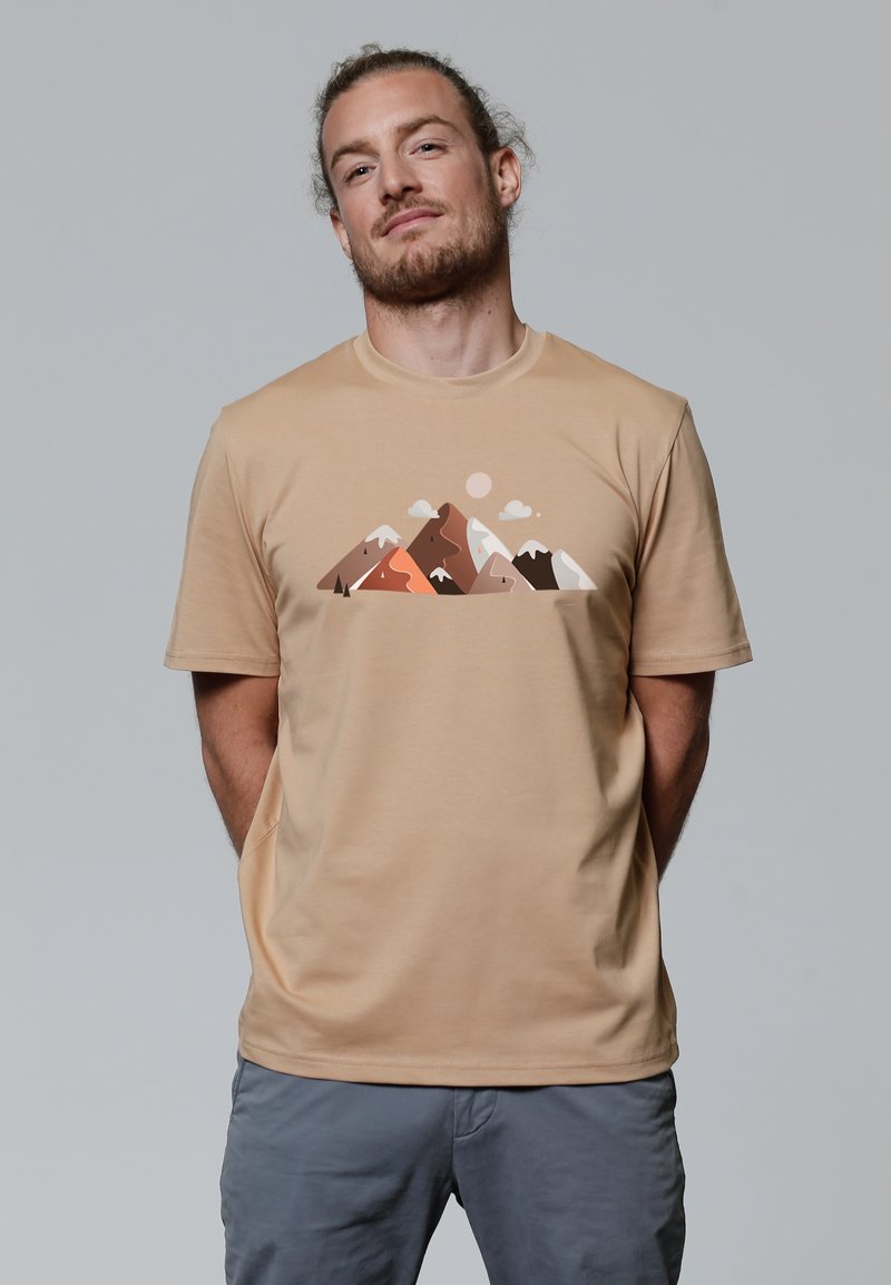 Beige t-shirt met een bergafbeelding in tinten bruin, oranje en wit, met korte mouwen en een ronde hals.