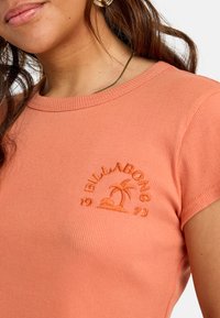T-shirt a coste corallo con maniche corte, dotato di un logo a forma di palma testurizzato e il numero "1973" ricamato in filo coordinato vicino al colletto.