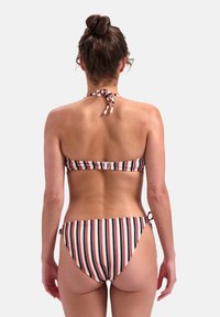 Bikini a righe con bande rosse, bianche e blu navy. Allacciatura sul retro per il top e anelli laterali per il fondo. Tessuto dalla consistenza morbida.