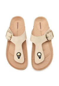 Sandalias beige con una correa ancha, herrajes de hebilla y un acento negro cerca del dedo del pie. Plantilla suave y texturizada, suela plana.