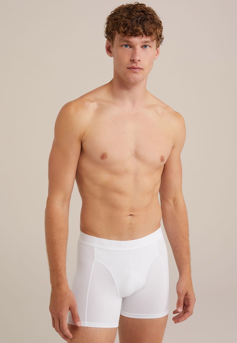 Boxers blancs présentés sur un modèle masculin, en coton doux avec une ceinture élastique comprenant un détail de logo.