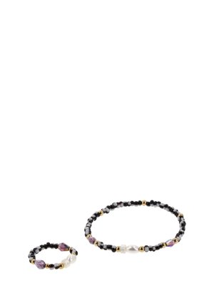 Két gyöngyös kiegészítő fehér háttéren: egy karkötő és egy kisebb gyűrű fekete, arany, lila és fehér gyöngyökkel, köztük egy gyöngyhöz hasonló gyönggyel.