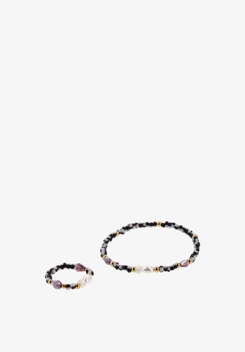 Deux accessoires perlés sur fond blanc : un bracelet et une bague plus petite avec des perles noires, dorées, violettes et blanches, y compris une perle ressemblant à une perle.