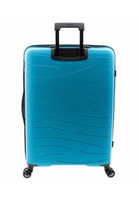 Maleta rígida de color azul brillante con patrones de olas texturizados, asa retráctil negra y cuatro ruedas que giran suavemente.