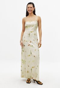 Maxi šaty z ľahkého krémového materiálu s kvetinovými vzormi v zelenej, oranžovej a žltej farbe. Majú tenké ramienka a priliehavý korzet.