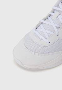 Λευκό αθλητικό παπούτσι με πλέγμα ανώτερο μέρος, λείες συνθετικές λεπτομέρειες, στρογγυλερή μύτη και επίπεδα κορδόνια. Σχεδιασμός με υφή και ελαφρύ βάρος.