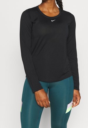 Svart långärmad atletisk topp med rund halsringning och diskret Nike-logotyp. Slätt, lätt tyg med en åtsittande silhuett och rynkade ärmdetaljer.