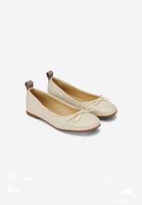 Helle beige Ballerinas aus weichem Leder, mit runder Spitze, kleinen Schleifendetails und einem braunen Absatzakzent. Geeignet für den Alltag.