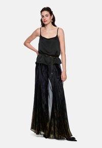 Black satin camisole with thin straps, paired with a long pleated skirt featuring a gradient of black to gold colors and a chain belt.
