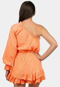 Een mini-jurk met één schouder, ruches in levendig oranje met een textuurstof en een elastische taille. Kenmerkt een lange mouw aan één kant en een gelaagde zoom.