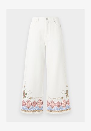 Pantaloni bianchi a gamba larga con chiusura a bottoni e zip, caratterizzati da motivi floreali e geometrici ricamati in rosso, blu, verde e marrone vicino all'orlo.