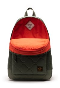Zeleni kvadratni ruksak s narančastim gornjim preklopom. Ima plavu unutrašnjost, logo oznaku i prednji džep s patentnim zatvaračem. Čist, moderan dizajn.