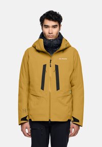 Giacca impermeabile gialla senape con accenti neri, chiusura con zip, cappuccio regolabile e molteplici tasche per lo stoccaggio.