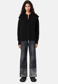 Suéter negro de gran tamaño con cuello, con dobladillo y mangas acanaladas. Combinado con jeans negros de pierna ancha y desgastados, y zuecos negros.
