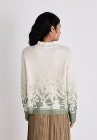 Strickpullover mit einem cremefarbenen Körper und einem grünen Blumenmuster am Saum, geripptem Kragen und Bündchen sowie einer lässigen Passform.