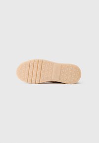 Semelle de chaussure beige clair avec un motif de semelle géométrique, rainures horizontales près des orteils et le nom de la marque "Gabor" embossé près du talon.