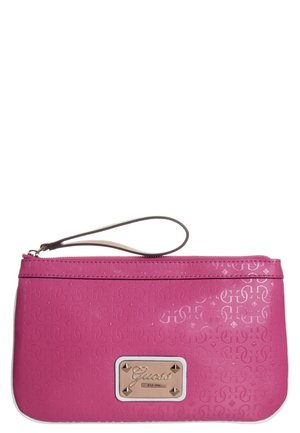 Pink wristlet clutch with embossed pattern, a zip closure, and a rectangular gold logo plate reading "Guess EST 1981" on the front.