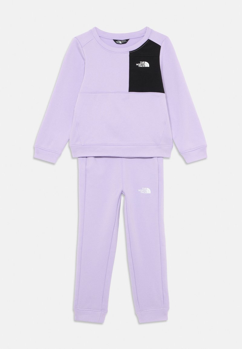 Fioletowy zestaw dresowy zawiera bluzy typu crewneck z czarną kieszonką na piersi i logo, w zestawie z pasującymi spodniami dresowymi z logo na nodze.