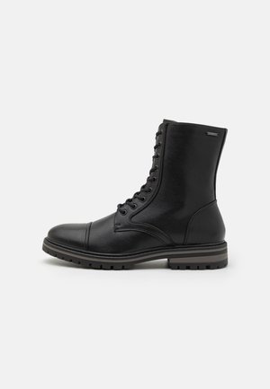 Black leather lace-up ankle boot with rugged sole and rounded toe, side view on plain light background.