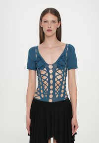 Μπλε δίχτυ σώματος με κοντά μανίκια, βαθύ V-λαιμό, κομμένα κύκλους και σταυρωτές λεπτομέρειες; σε συνδυασμό με μια μαύρη φαρδιά φούστα.