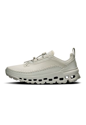 Zapatilla deportiva gris claro con parte superior de tela suave, detalle de costura texturizada y suela acolchada con orificios de ventilación.