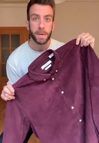 Viininpunainen napillinen paita, joka on valmistettu pehmeästä, teksturoidusta kankaasta, jossa on mandariinikaulus ja valkoiset napit, pidettävänä valkoista paitaa käyttävän henkilön toimesta.