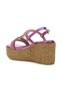 Sandali wedge metallici rosa con platform in paglia intrecciata. Presentano un design con cinghie incrociate e una cinghia alla caviglia con fibbia. Texture liscia.