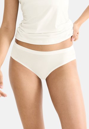 Lichtbeige hipster slipjes met een zachte tailleband. Gemaakt van soepel materiaal met minimaal naden voor comfort. Een bijpassende top is gedeeltelijk zichtbaar.
