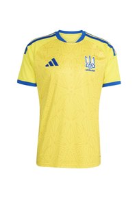 Žuta nogometna majica s plavim detaljima, plavi Adidas logo na desnoj strani grudi i grb Ukrajine na lijevoj strani grudi s suptilnim geometrijskim uzorkom.
