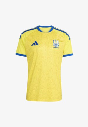 Žuta nogometna majica s plavim detaljima, plavi Adidas logo na desnoj strani grudi i grb Ukrajine na lijevoj strani grudi s suptilnim geometrijskim uzorkom.