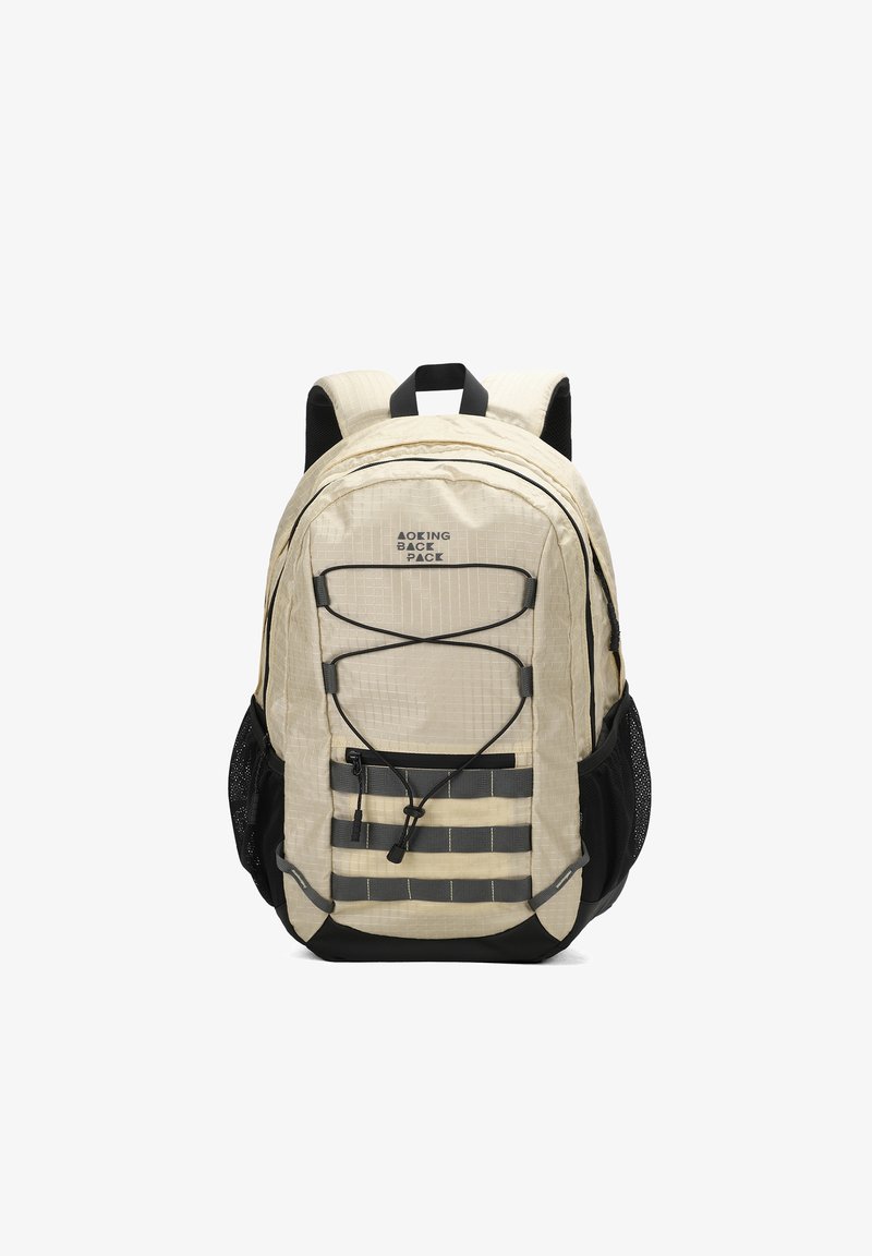 Sac à dos beige avec surface texturée, accents noirs, bretelles réglables, cordon bungee à l'avant et poches latérales en mesh pour le rangement.