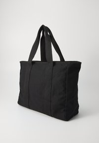 Czarna torba na ramię z płótnem, z materiałowymi uchwytami, prostokątny kształt, teksturowana powierzchnia i strukturalny design. Brak widocznych okucji lub akcentów.