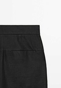 Jupe noire taille haute avec une large ceinture et des détails discrets de coutures sur un fond blanc uni.