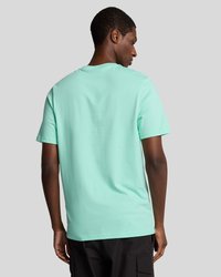 Mátově zelené bavlněné tričko s kulatým výstřihem a krátkými rukávy, s volným střihem a hladkou texturou. Pohled zezadu zdůrazňuje jednoduchost.