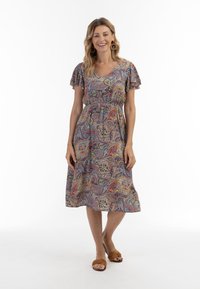 Květinové paisley šaty v mnoha barvách, krátké volánkové rukávy, výstřih do V, elastický pas, délka ke kolenům, doplněné hnědými sandály na slip-on.