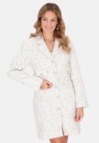 Fehér tweed ruha fekete és arany kiegészítőkkel, testhezálló fazon, egysoros kivitel, kihajtott gallér és négy gombos záródás.