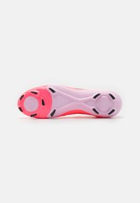 Vista inferiore di una suola di scarpa atletica rosa e viola con tacchetti di trazione neri e una sezione centrale liscia su uno sfondo bianco.
