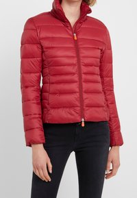 Rode donzen jas met een hoge kraag, horizontaal doorgestikte patroon, een ritssluiting aan de voorkant met een oranje trekker en twee zijzakken.