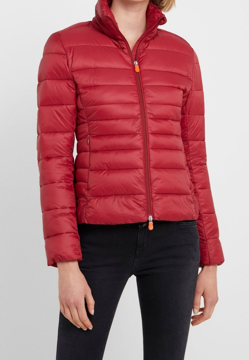 Rode donzen jas met een hoge kraag, horizontaal doorgestikte patroon, een ritssluiting aan de voorkant met een oranje trekker en twee zijzakken.