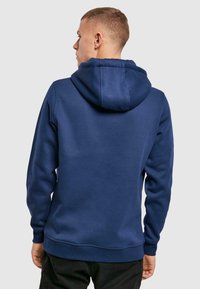 Marineblaues Sweatshirt mit Kapuze, ausgestattet mit einer weichen Textur, gerippten Bündchen und einem gerippten Saum. Einfaches Design ohne Muster oder Logos.