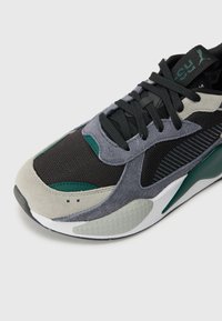 Sportliche Schuhe mit einem Obermaterial aus Mesh und Wildleder in Schwarz, Grau und Türkis, ausgestattet mit einer strukturierten Sohle und einem markanten Schnürsystem für zusätzlichen Halt.