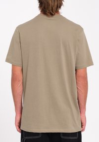 Beige bomulds t-shirt med korte ærmer, rund halsudskæring og en glat overflade. Simpelt design, ingen synlige mønstre eller detaljer på ryggen.