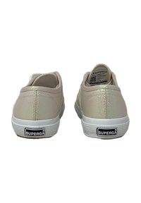 Sneaker rosa chiaro con una texture lucida, suola in gomma bianca e design posteriore liscio con etichetta del logo.
