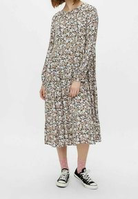 Blommig långärmad klänning i lätt tyg, med ett flerfärgat mönster av små blommor, lös passform och rund halsringning. Kombinerad med svarta sneakers.