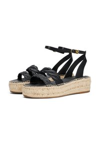 Mustat espadrille-sandaalit, joissa on punottuja nahkaremmejä, juuttikuidusta kudottu alusta ja nilkkaremmi, jossa on kultainen solki.