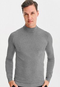 Szary sweter z golfem, wykonany z miękkiego, dzianinowego materiału, z długimi rękawami, dopasowanym krojem oraz prążkowanym kołnierzem i dołem.